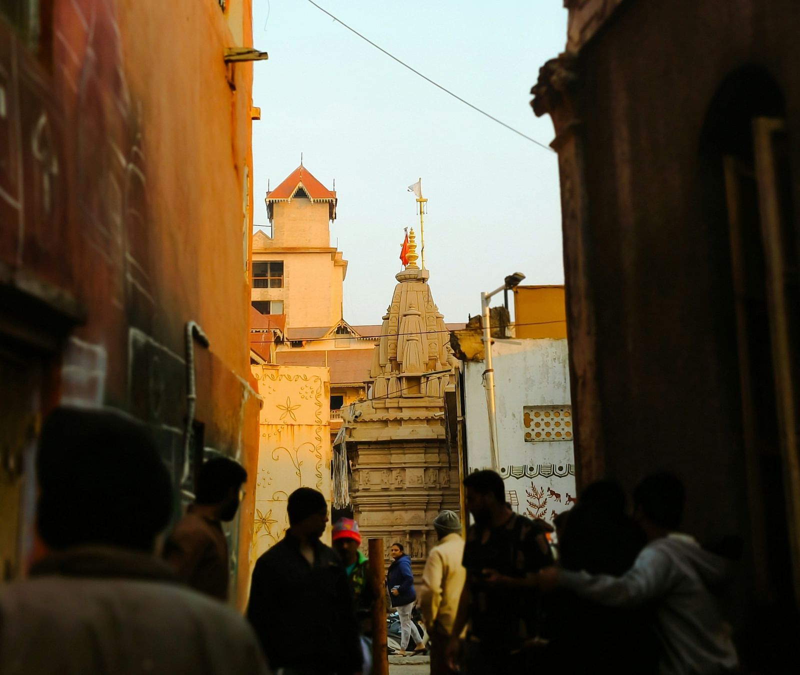 A dimly lit street with the silhouette of people walking in front.