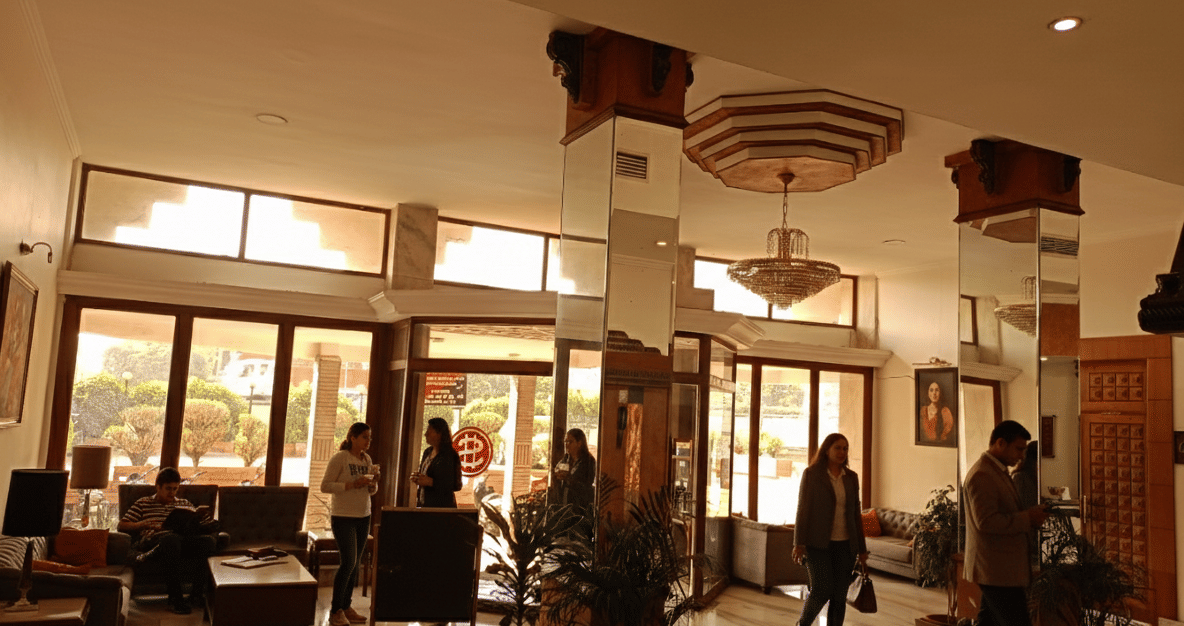 Lobby area at Hotel Gold, Panipat with seating, large windows, and guests walking through the space.