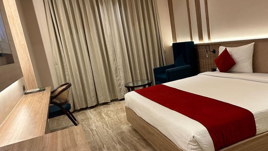  Elegant room at Hotel City Inn, Varanasi, with chic curtains, comfy seating, and a modern bed setup in warm tones.
