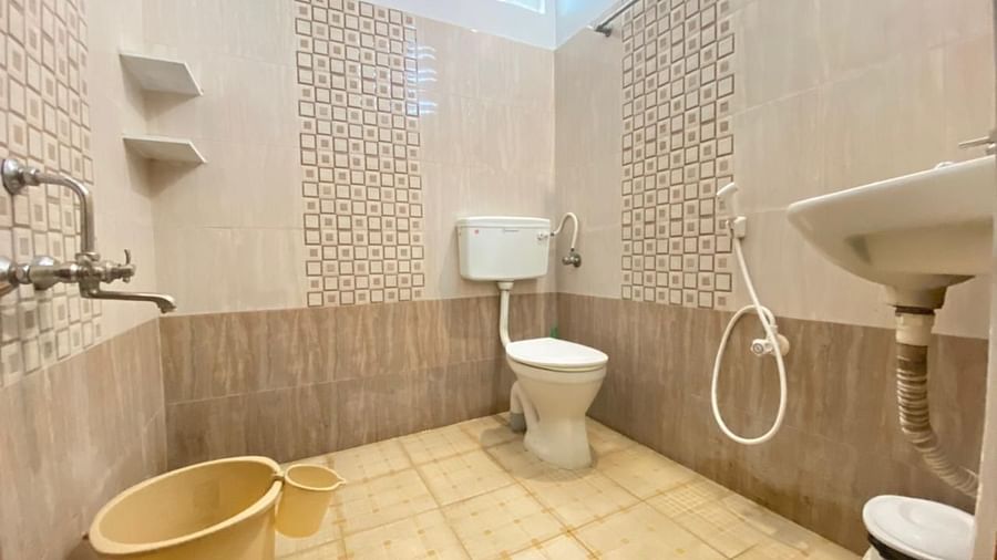 A washroom with a sink, toilet and bucket | La Paradise Residency | Hotel in Pondicherry