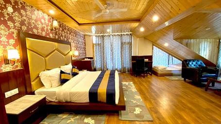 Image of an expansive room with wooden furnishing featuring a double bed and one single bed | DLS La Serene Manali