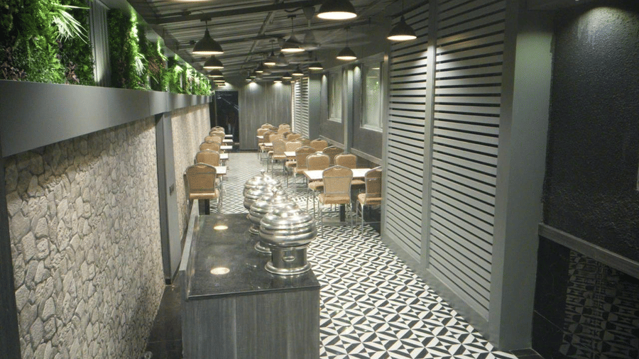 A buffet arrangement on the table set against patterned rock wall featuring a marble floor and seating space at the backdrop.