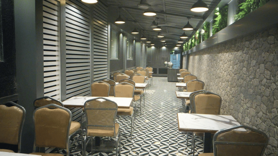 Multiple dining table set on a narrow hallway featuring patterned marble floor and pendant lights at Shyanu Lords Eco Inn Airoli.