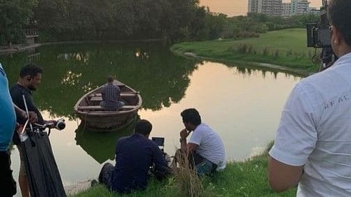 A lake surrounded by greenery while people are working for a photoshoot - Karma Lakelands, Gurgaon