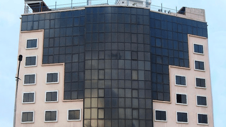 A wide shot of a multi-storey, modern building with a sign on top.