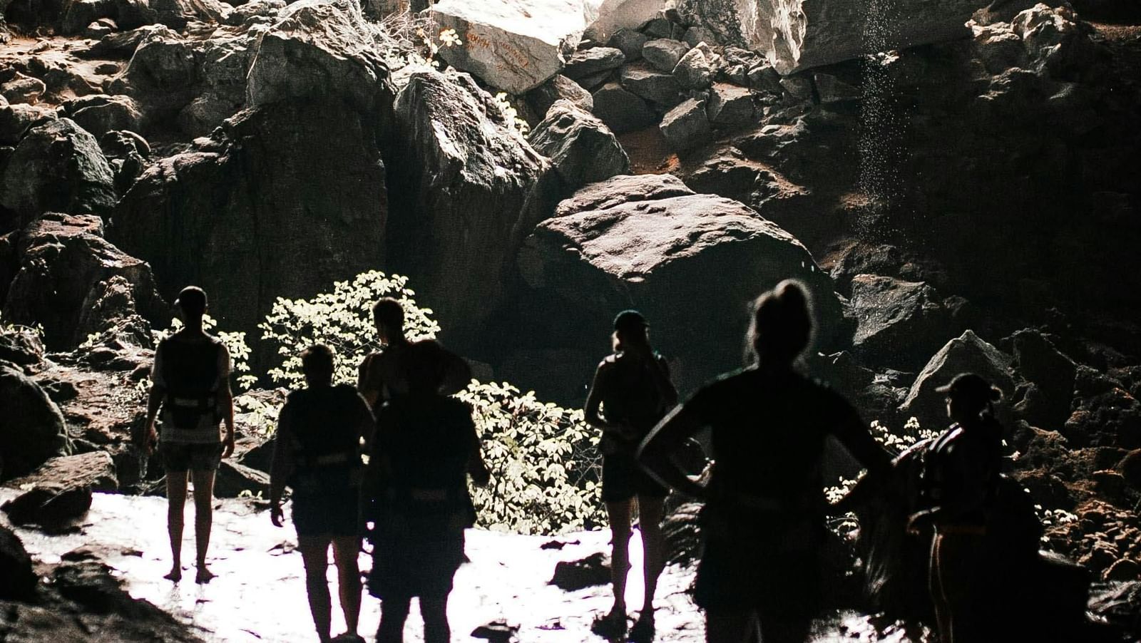 Back shot featuring the silhouette of several tourists leaving a cave.