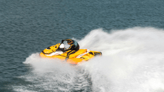 A person riding a speedboat on a clear, blue day