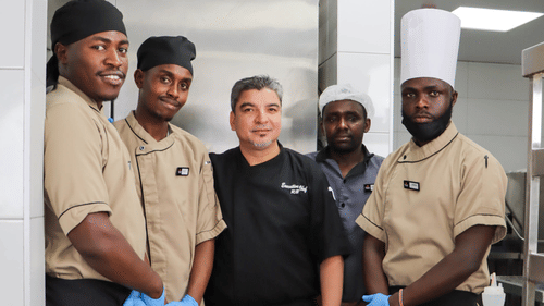 Group of restaurant staff standing with a food trolley in a kitchen at Asiatic Rooftop Bar and Restaurant.