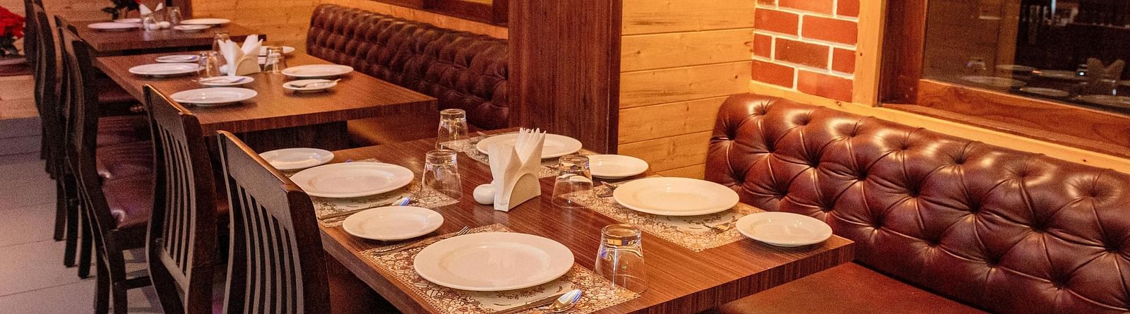 Corner view shot of the restaurant at Sumitel, Sanderling featuring a dining table with well arranged plates and cutlery.
