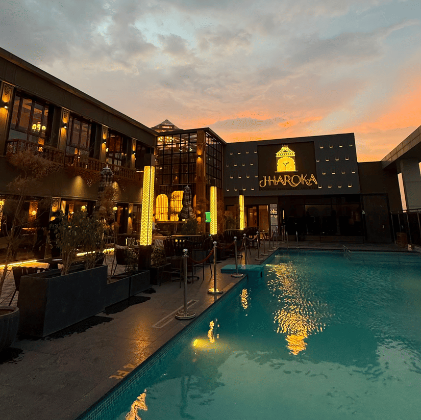 A swimming pool of Jharoka situated next to a building structure under a sky during twilight.