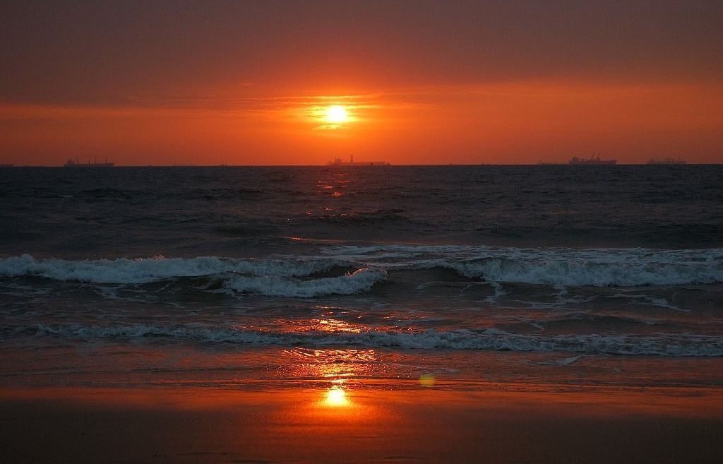 A sunset at the beach as the waves are crashing the shore and the water is golden due to the sunlight