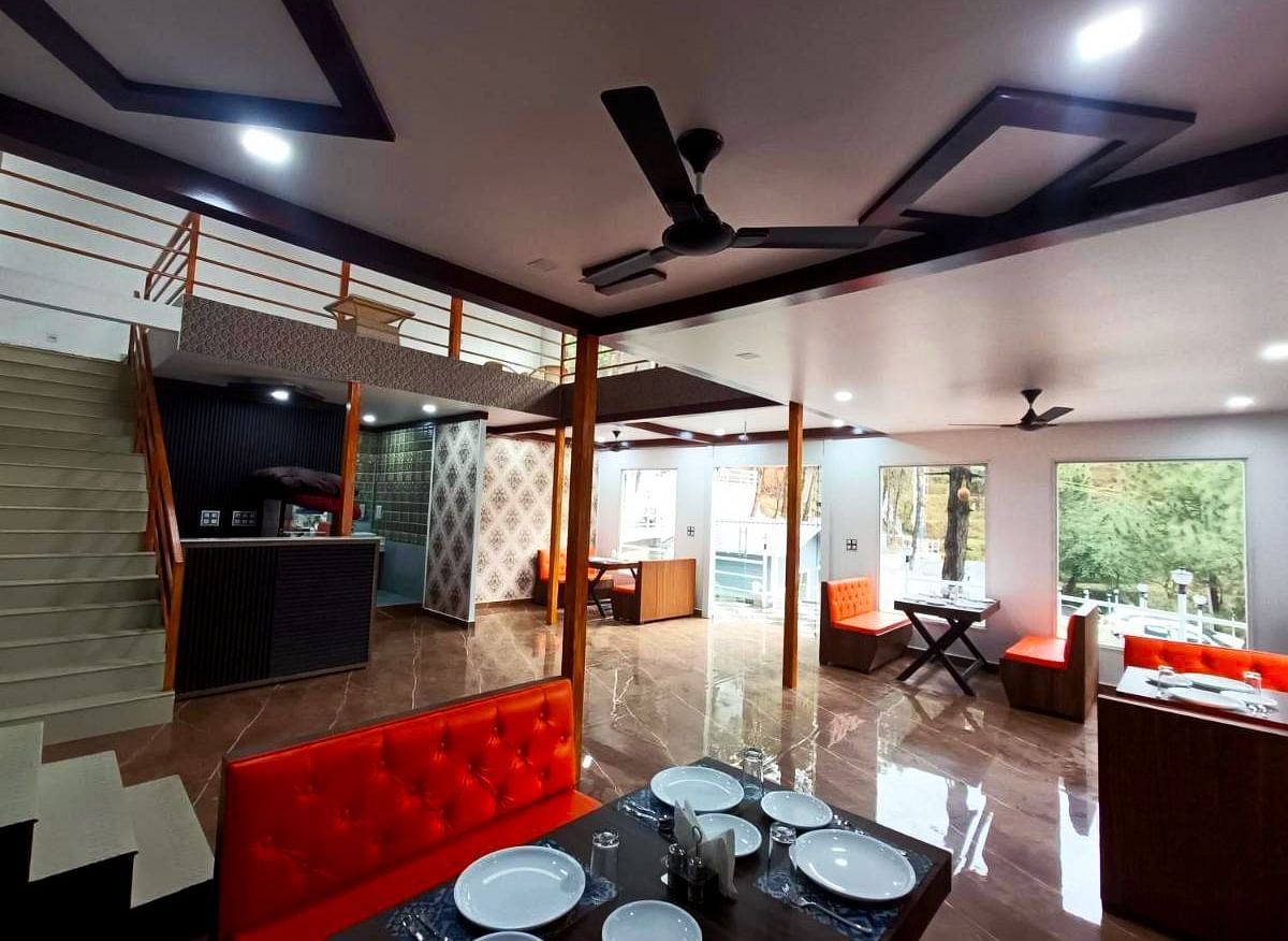 The interiors of the restaurant at DLS Nature Trinket Resort with red couches and tables.