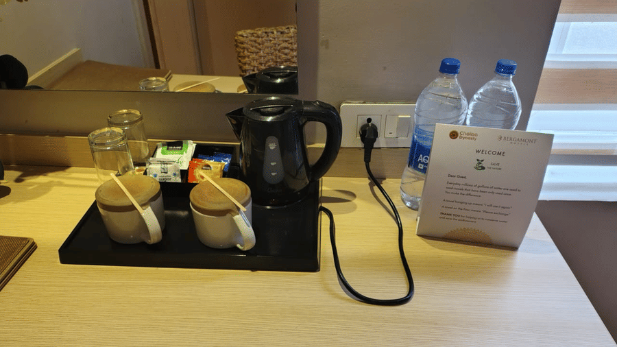 Tea and coffee maker at Lawn View Room at Cholaa Dynasty, Kumbakonam. It also features two cups with lids and mineral water bottles.