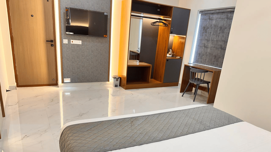 A bedroom with a double bed, open wardrobe, work desks, and a window with a grey blind | Hotel Aurora Bliss