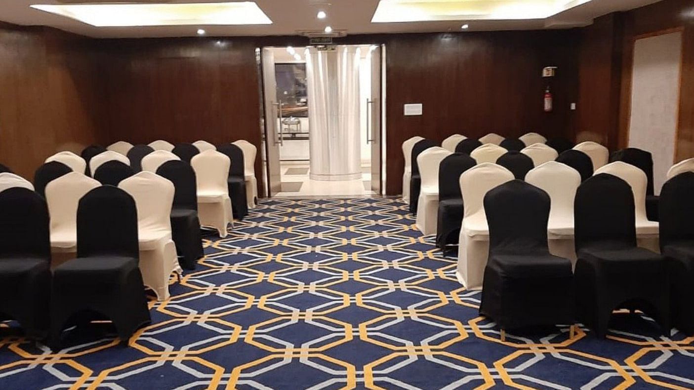 A well-arranged conference hall at the banquet hal, The Cunningham Hotel, featuring elegant black and white chairs, a vibrant geometric-patterned carpet, warm lighting, and a sophisticated ambience