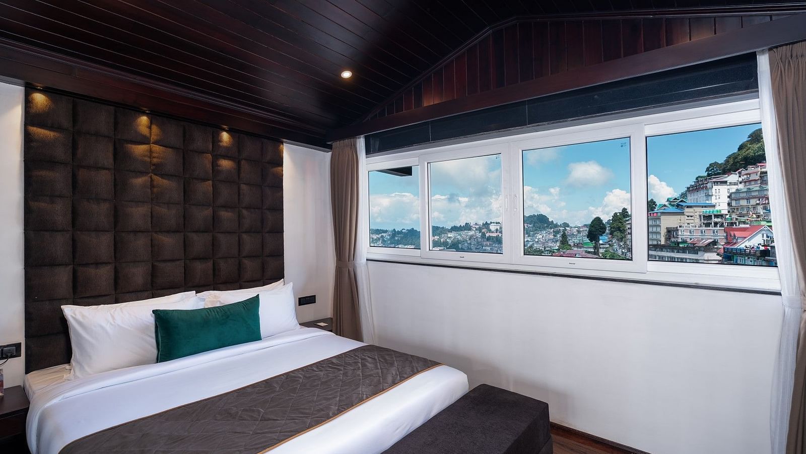 Image of a bedroom with a king size bed and a window that overlooks the city. 