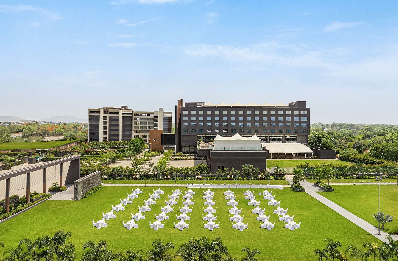 Aerial view of Essentia Luxury Hotel, Indore with a lawn in front of the hotel building