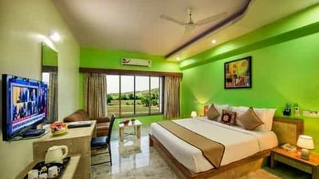 A brightly coloured room with a double bed, a television, and a balcony - Lion Lords Inn Rajula