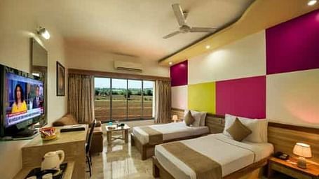 A modern room featuring twin beds with colourful wall panels and a television - Lion Lords Inn Rajula