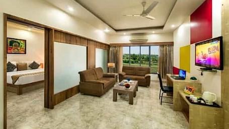 A spacious room including a seating area with sofas, a television, and large windows - Lion Lords Inn Rajula