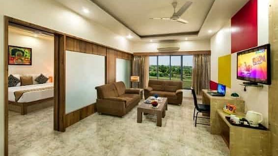A spacious room including a seating area with sofas, a television, and large windows - Lion Lords Inn Rajula