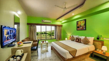 A brightly coloured room with a double bed, a television, and a balcony - Lion Lords Inn Rajula