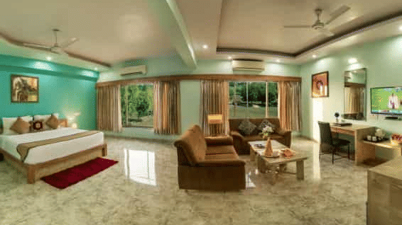 A colourful room offering a double bed, a seating area with sofas, and a television - Lion Lords Inn Rajula