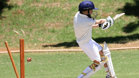 A close view of the cricketer batting on a green cricket field.