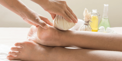 A poultice on the ankle of a person lying next to containers with liquids in them