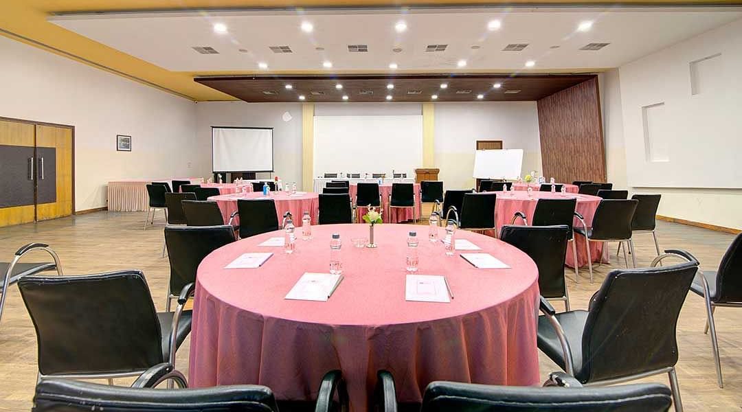 a banquet hall with cluster style seating and round tables - Camel Valley Resort, Igatpuri