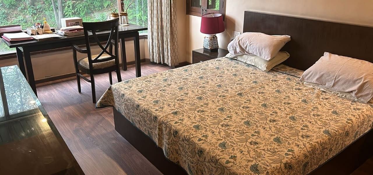 A large bed near a nightstand with a view of trees at Presidential Suite at SOUTHGATE KASAULI BY ZENQ.