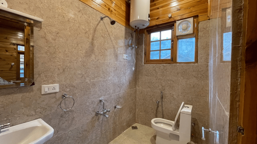 A bathroom at Dawat e Drung by FrozenFall Resort, Drung, Tangmarg, featuring a toilet, a sink, a shower fixture, and a wall-mounted water heater.
