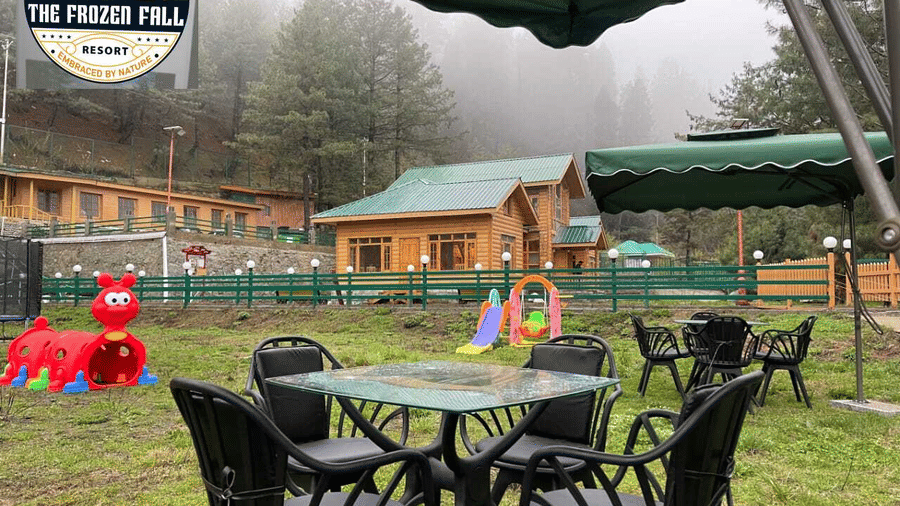 An outdoor courtyard view at Dawat e Drung by FrozenFall Resort, Drung, Tangmarg, featuring 1 glass-topped table, 4 chairs and a misty atmosphere.