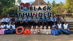 Group photo of visitors in front of the iconic Black Thunder signboard with joyful expressions.