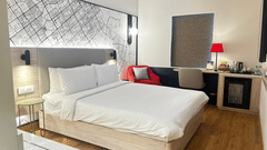 Modern guest room at Hometel, Chandigarh with king bed, city map feature wall, red armchair, work desk and minibar.