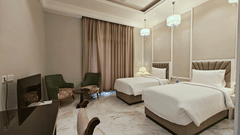 two single beds in a bedroom with a workdesk and chairs to sit - Sarovar Portico, Saharanpur