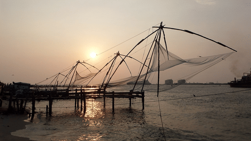Fort Kochi Beach featuring Chinese fishing nets being used during sunset to catch fish