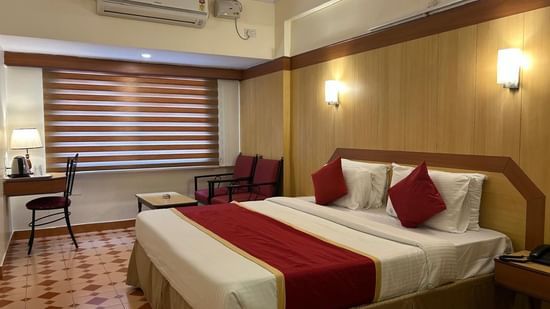 Spacious guest room at Hotel Swagath, Bangalore with two twin beds, cushioned headboards, and warm lighting.