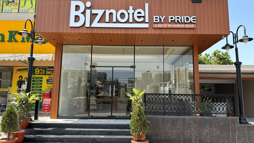 Exterior view of the main entrance and signage of Biznotel by Pride Surat with potted plants.
