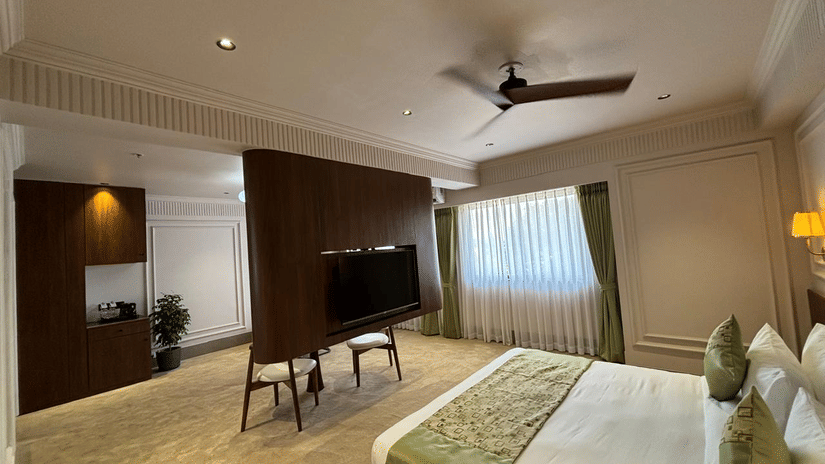 Spacious executive hotel suite at Biznotel by Pride Surat featuring a king bed, central TV partition, and modern furnishings.