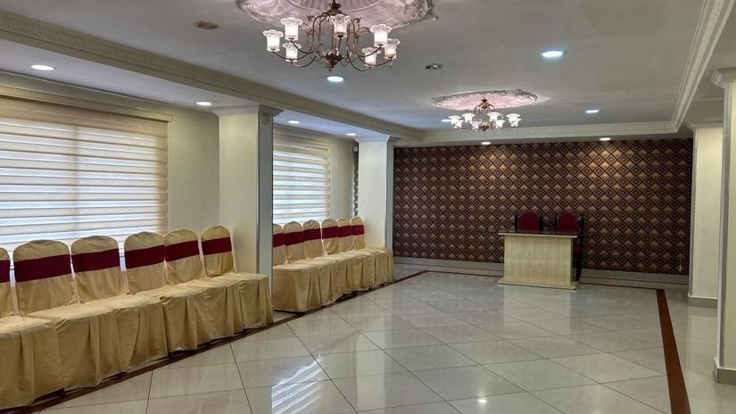 Banquet hall at Hotel Swagath, Bangalore with stage, chandelier ceiling lights, and ample seating for events.
