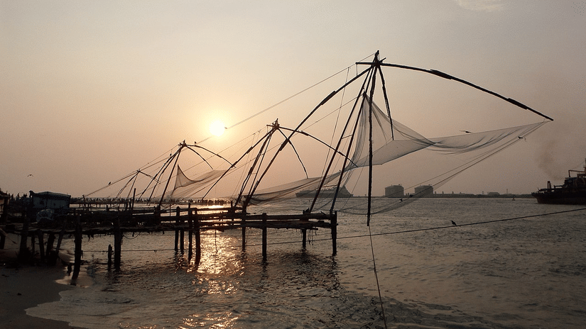 Fort Kochi Beach featuring Chinese fishing nets being used during sunset to catch fish