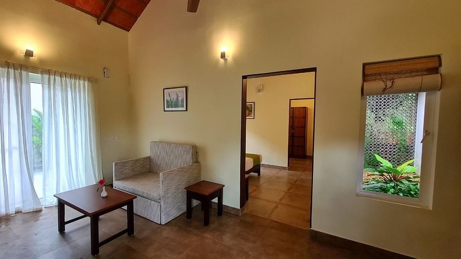 A living area features a sofa, table, and a doorway leading to another room.- Abad Brookside Lakkidi, Wayanad