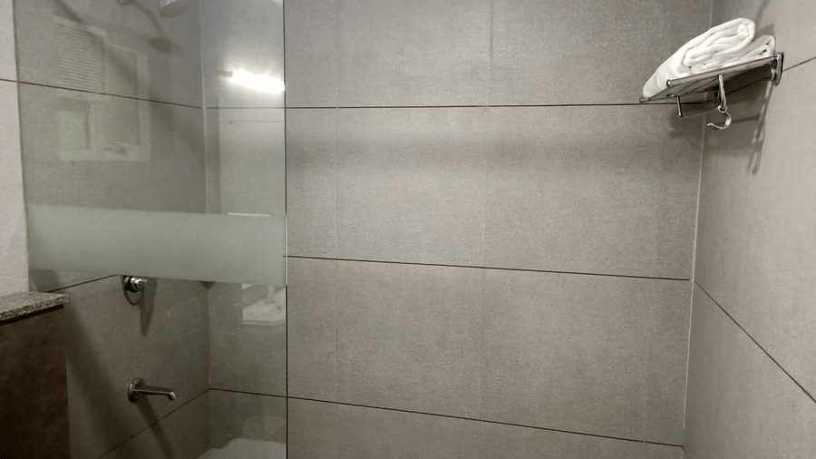 A shower stall features a glass door and a shower head.- Abad Brookside Lakkidi, Wayanad