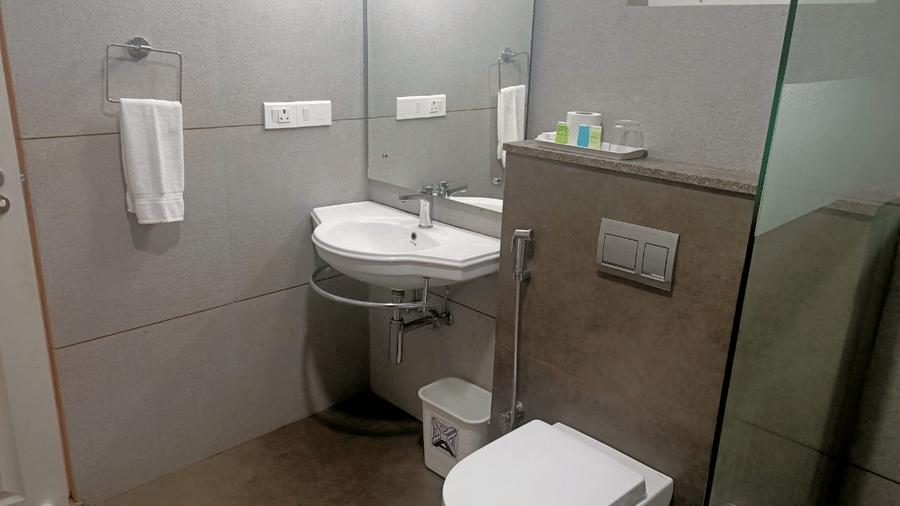 A view of the bathroom shows the toilet and sink from a different angle.- Abad Brookside Lakkidi, Wayanad