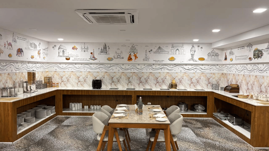 Buffet counter at Biznotel by Pride Surat arranged around a central dining setup with colourful wall motifs.