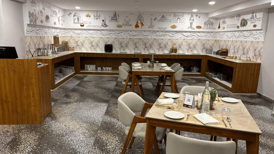 Modern restaurant dining setup at Biznotel by Pride Surat featuring set wooden tables and patterned flooring.