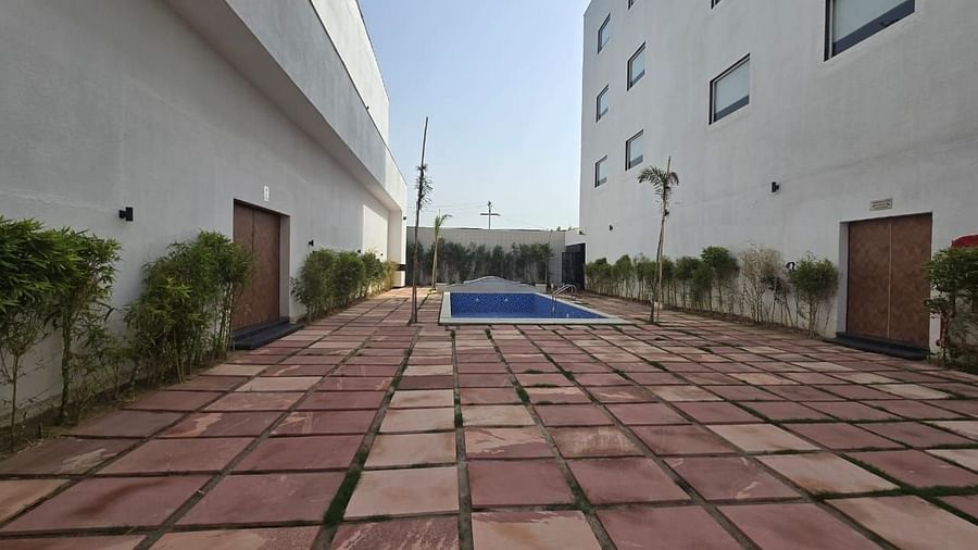 A wide shot of the pool area at Clarks Inn Express, Firozabad, featuring a pool with buildings on either side. 