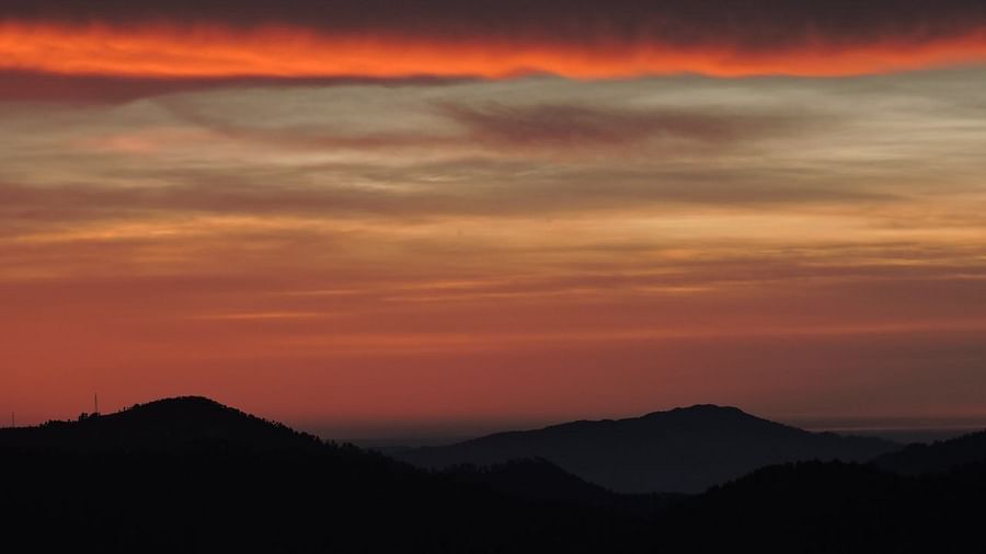 The setting sun casts a warm glow over layered clouds and mountain silhouettes, creating a picturesque and serene landscape, possibly a view from the resorts vicinity