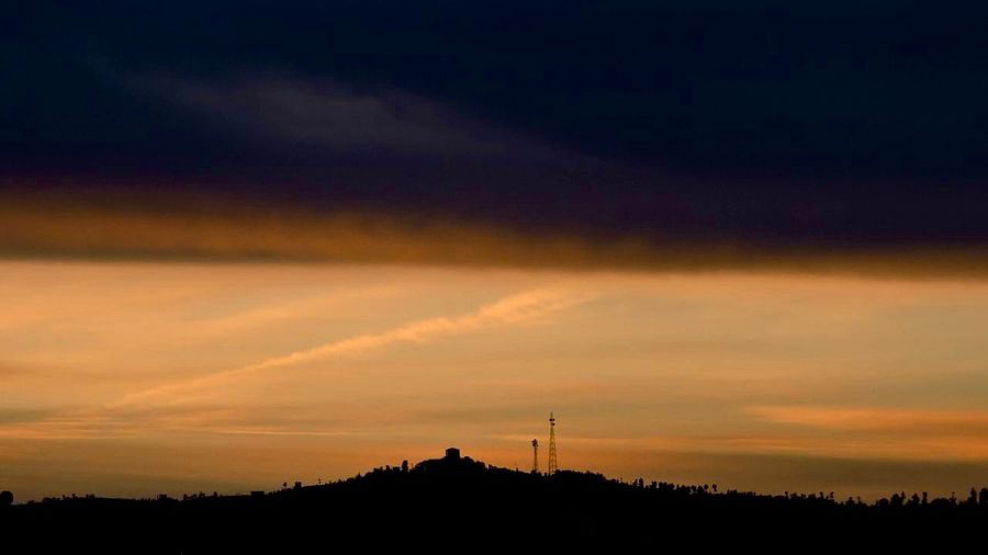A moody sky, filled with dark, dramatic clouds, hints at the fading light of sunset, with a silhouetted hill adding depth and contrast to the scene, possibly captured near the resort